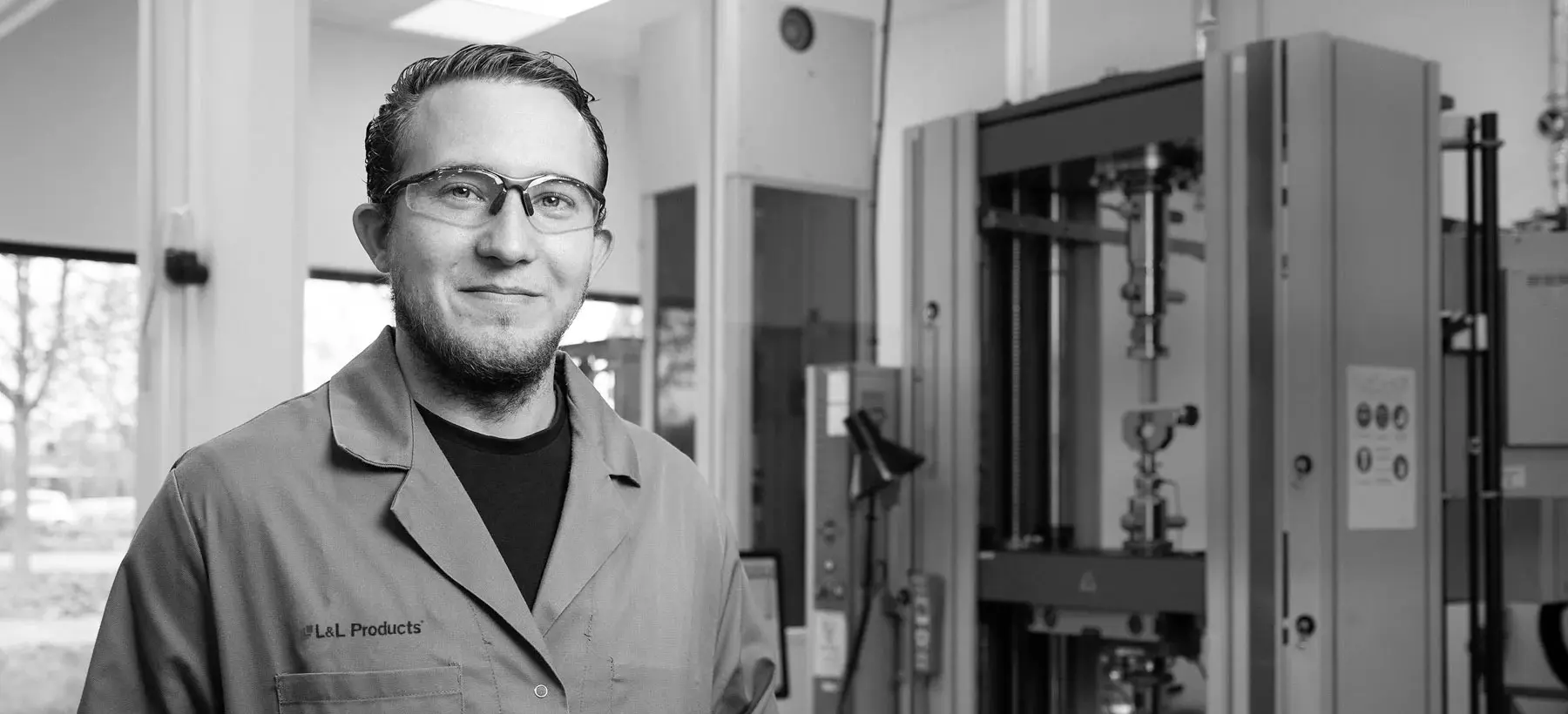 An L&L Products employee wearing a lab coat and smiling