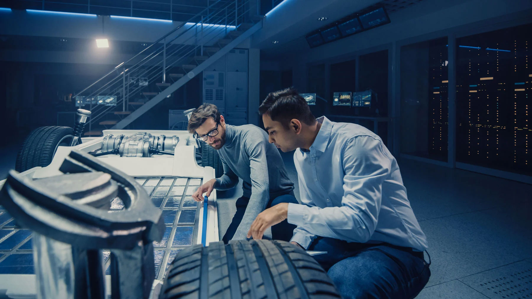 Two men taking measurements of a car frame