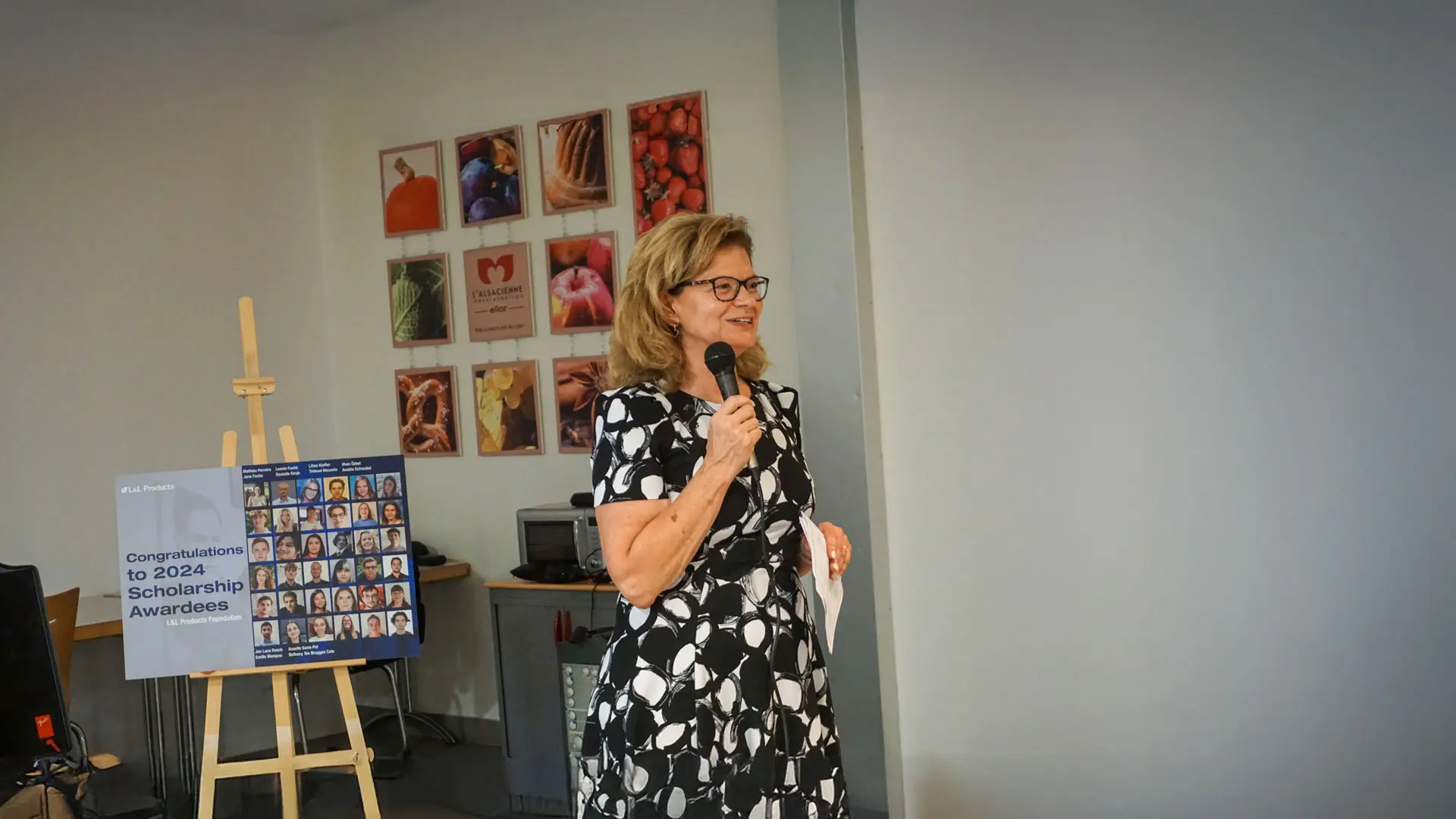 A woman holding a microphone is speaking to a group of people